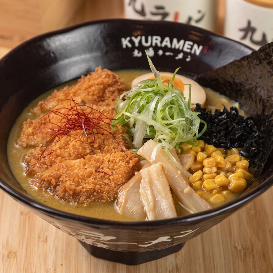 Japanese ramen bowl topped with crispy cutlet, scallions, corn, black fungus, bamboo shoots, chili threads, and nori.